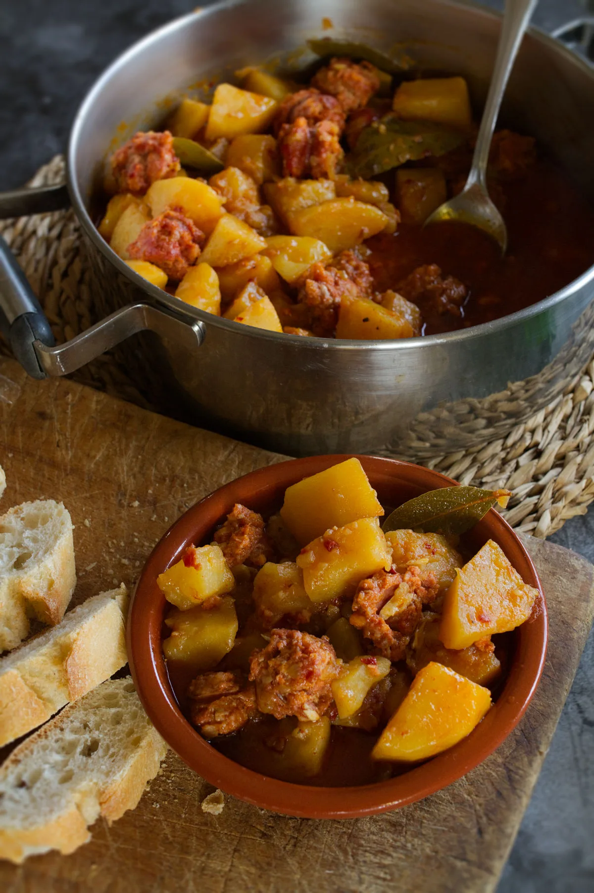 A large pot of Rioja-style potatoes with chorizo sits beside a small bowl serving.