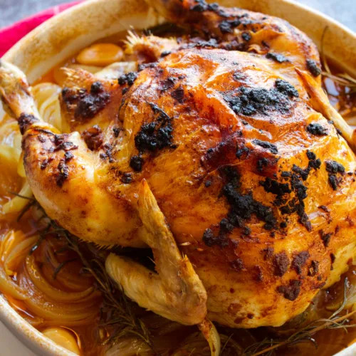 A Spanish roast chicken with a smoked paprika rub sits cooked in a large dish.