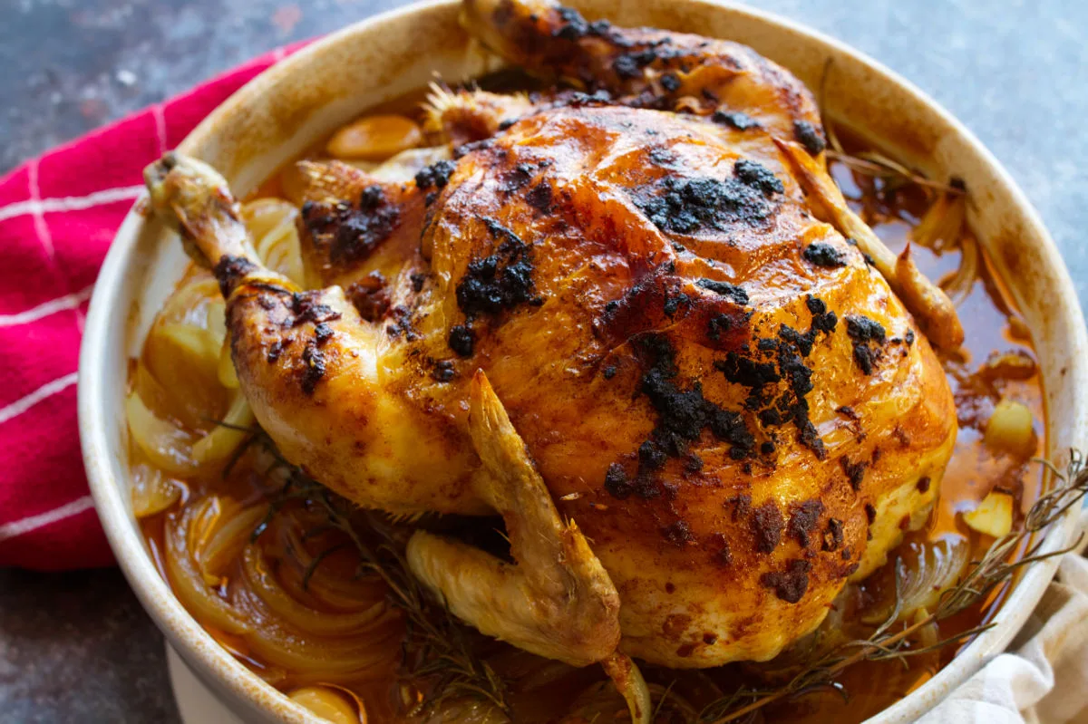 A Spanish roast chicken with a smoked paprika rub sits cooked in a large dish.